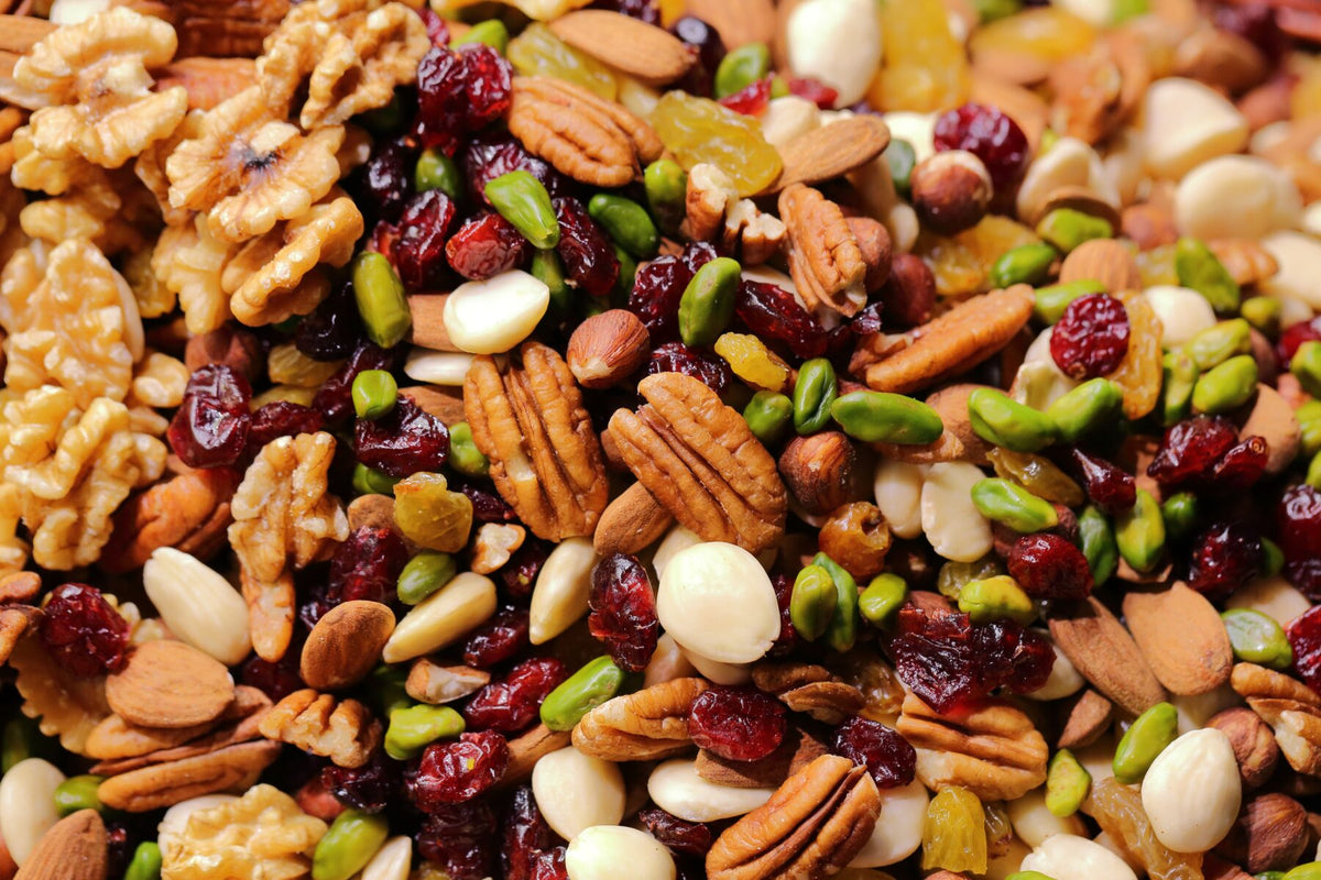 Gemischte Nüsse wie Mandeln, Walnüsse, Cashewkerne und Pistazien liegen auf einer hellen Fläche