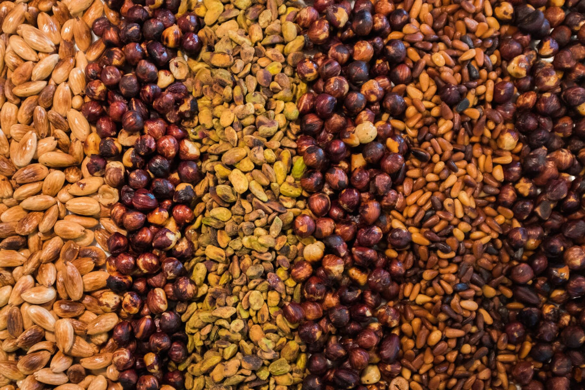 Mandeln, Walnüsse, Cashewkerne, Haselnüsse und Pistazien nebeneinander auf einer hellen Fläche